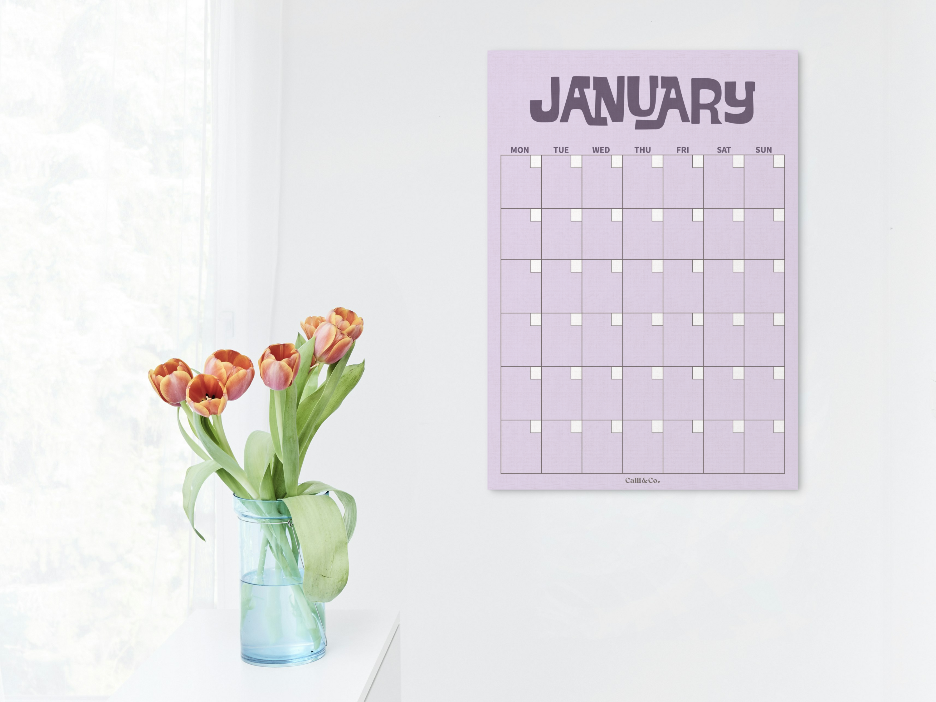 Purple January calendar on a white wall with a vase of tulips.